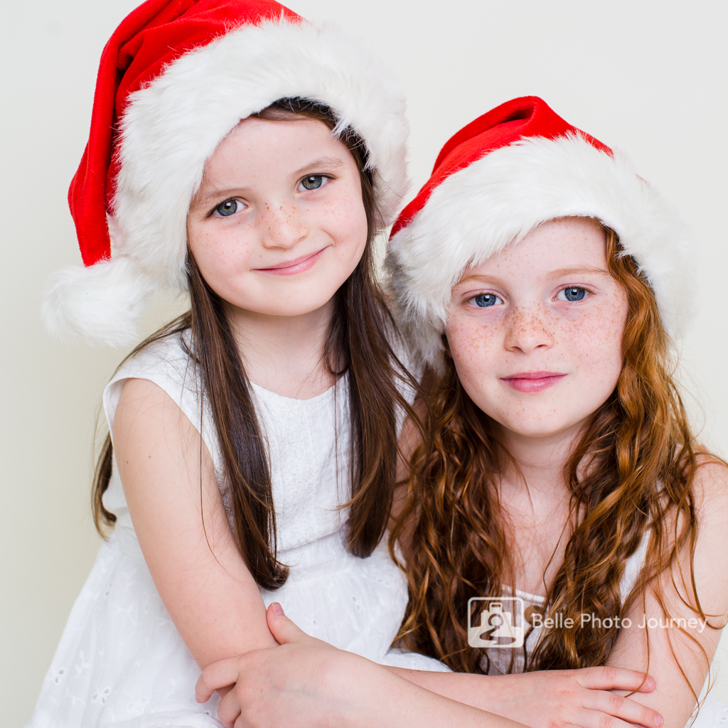 Sisters cuddling each other Christmas Santa hats pic