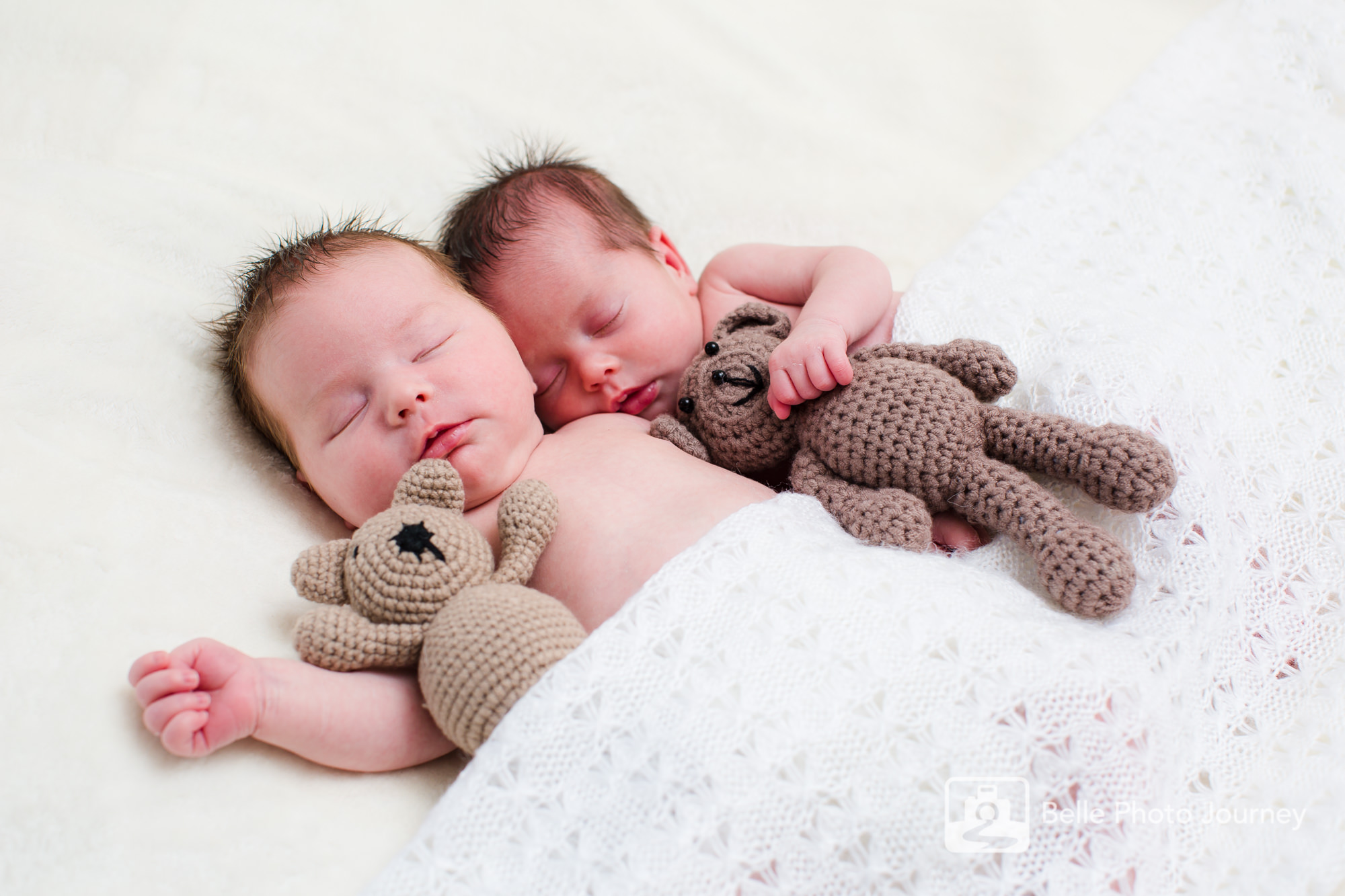 newborn twins cuddling teddy bears